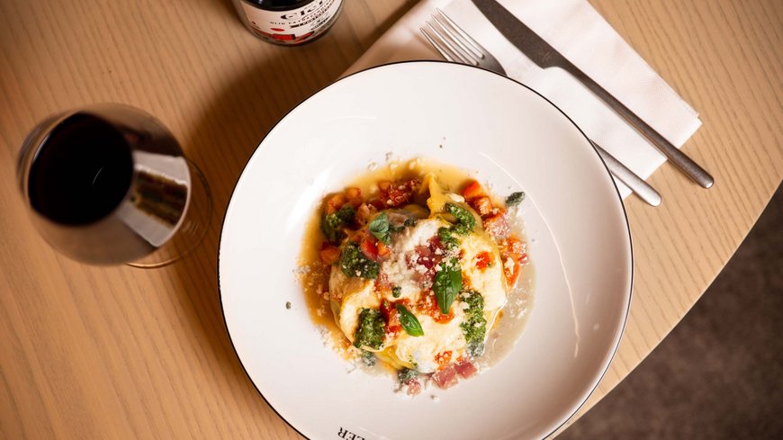 Exzellent essen in diesem Restaurant in Sterzing Pasta mit Tomaten, Pesto und Käse auf einem weißen Teller mit Wein und Besteck