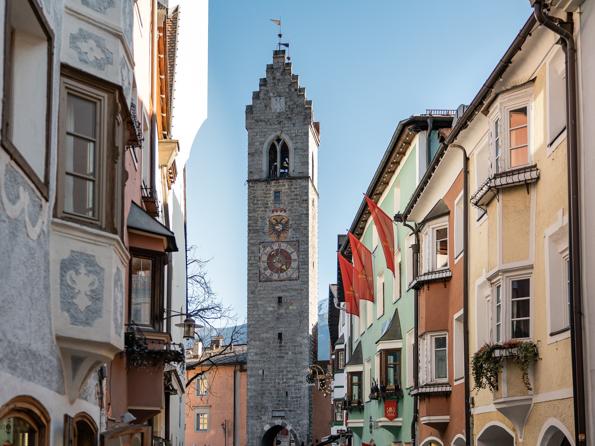 Well-being at the Schwarzer Adler Historic clock tower and colorful houses in an old town street under clear sky