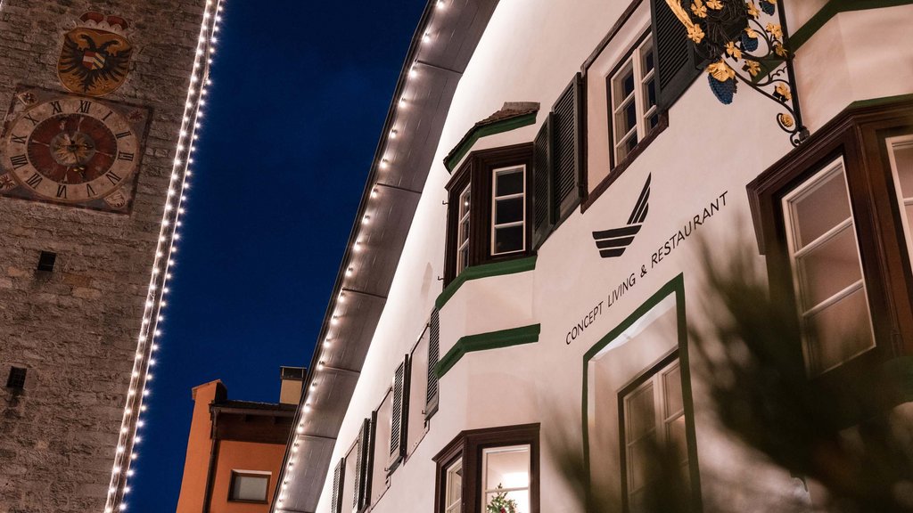 The laid-back town on the Isarco/Eisack river Illuminated facade of a restaurant next to a historic tower at night