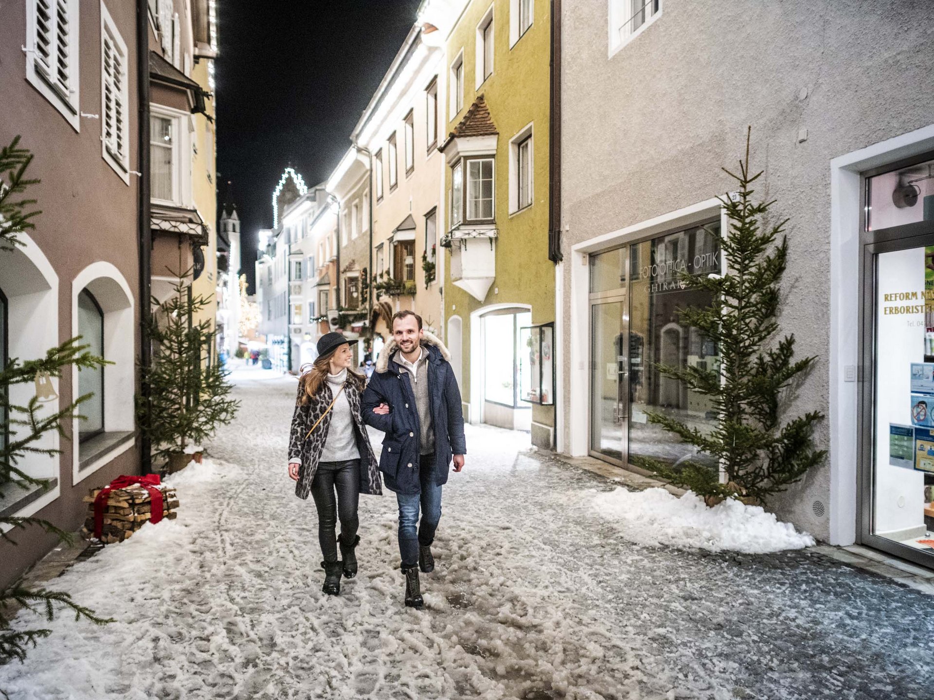 The perfect location for your apartment in Sterzing Couple walking at night through snowy, festively lit old town street