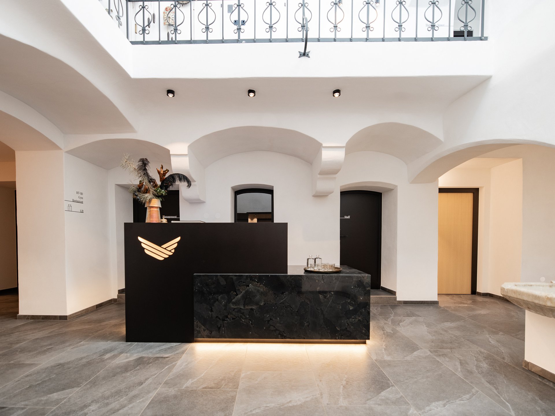 Charmantes Boutique Hotel in Sterzing Moderner schwarzer Empfangstresen in einem weißen, hellen Hotelfoyer