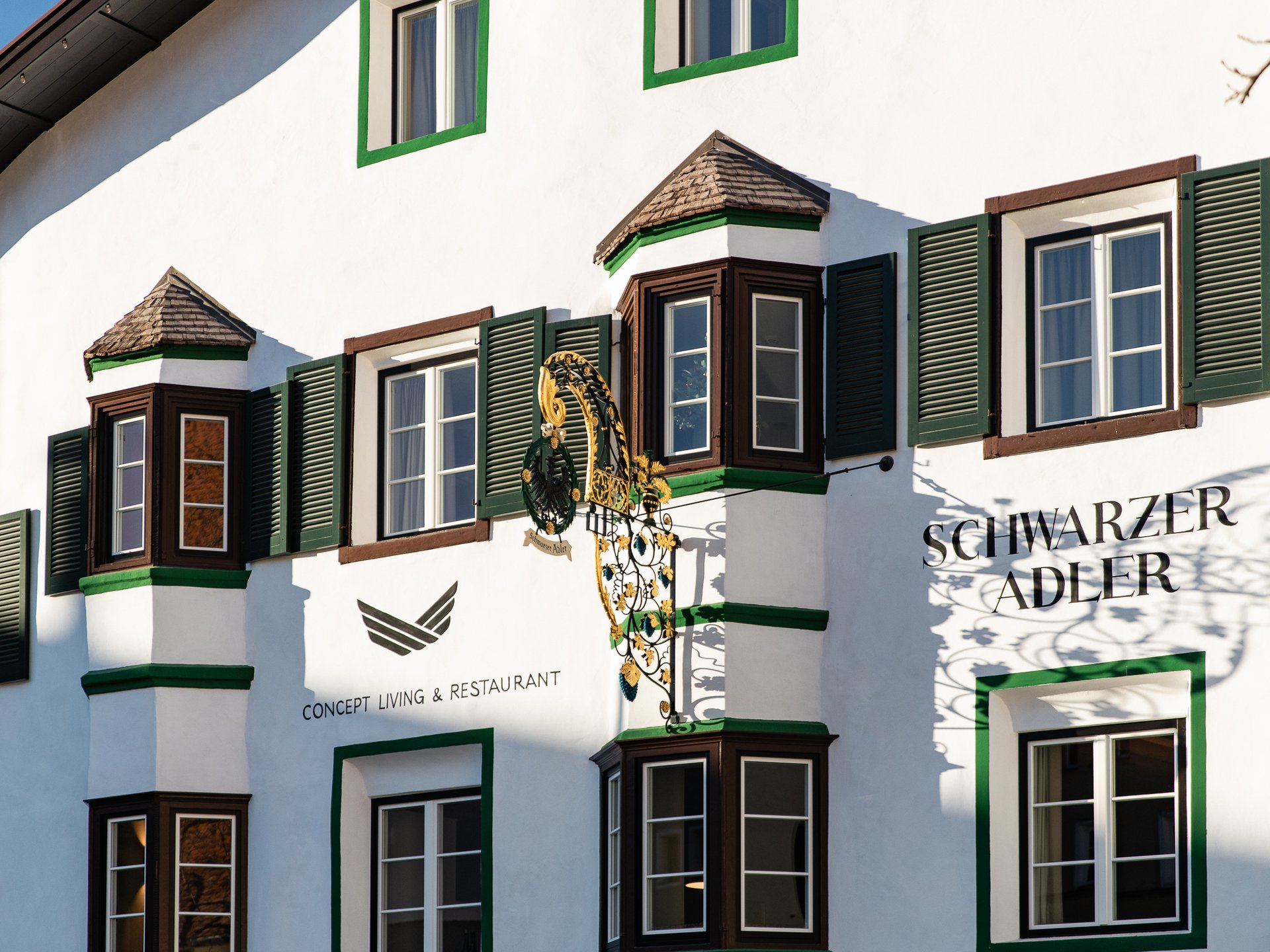 Cooles Rennradhotel in Südtirol Fassade eines Restaurants mit grünen Fensterläden und goldener Zier am Gebäude