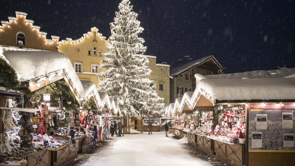 The perfect location for your apartment in Sterzing Christmas market with snow-covered stalls and illuminated Christmas tree at night