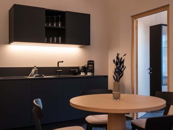 Schwarzer Adler Sterzing: A historic icon. Reinvented. Moderne Küchenzeile mit schwarzen Schränken und rundem Holztisch