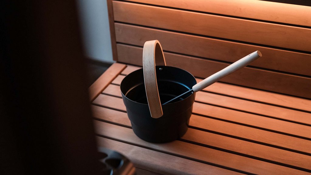 Well-being at the Schwarzer Adler Sauna bucket and ladle on a wooden bench inside a sauna