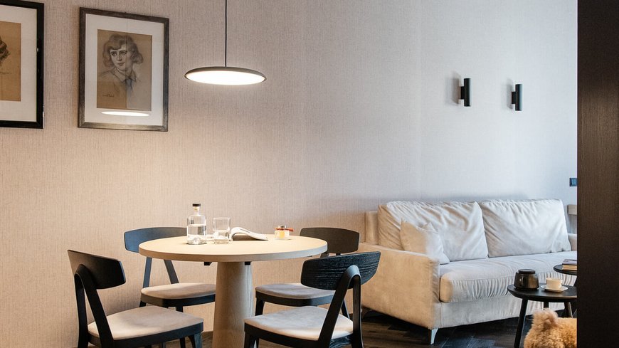 Schwarzer Adler Sterzing: A historic icon. Reinvented. Modernes Wohnzimmer mit Tisch, Stühlen, Sofa und kleinem Hund auf Holzboden