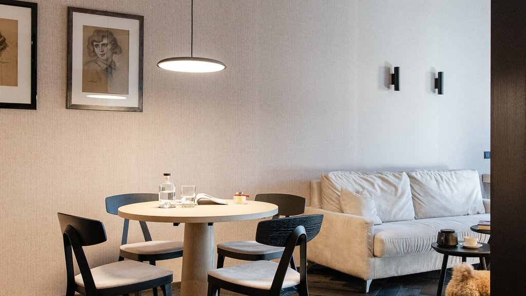 Schwarzer Adler Sterzing: A historic icon. Reinvented. Modernes Wohnzimmer mit Tisch, Stühlen, Sofa und kleinem Hund auf Holzboden