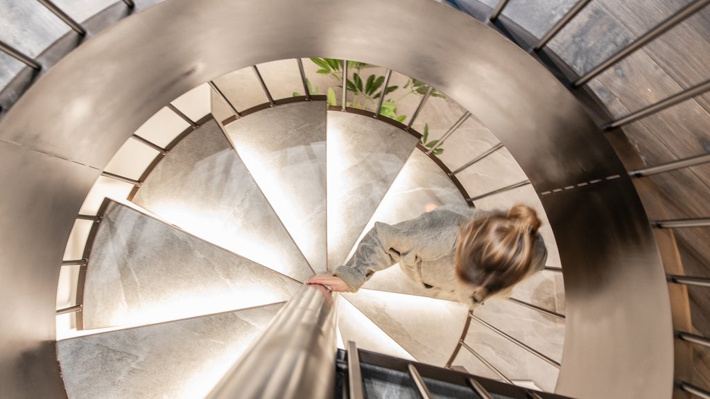 Schwarzer Adler Sterzing: A historic icon. Reinvented. Frau steigt eine beleuchtete Wendeltreppe hinab