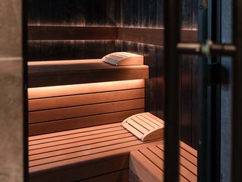 Schwarzer Adler Sterzing: A historic icon. Reinvented. Moderner Sauna-Innenraum mit Holzsitzen und Kopfstützen beleuchtet