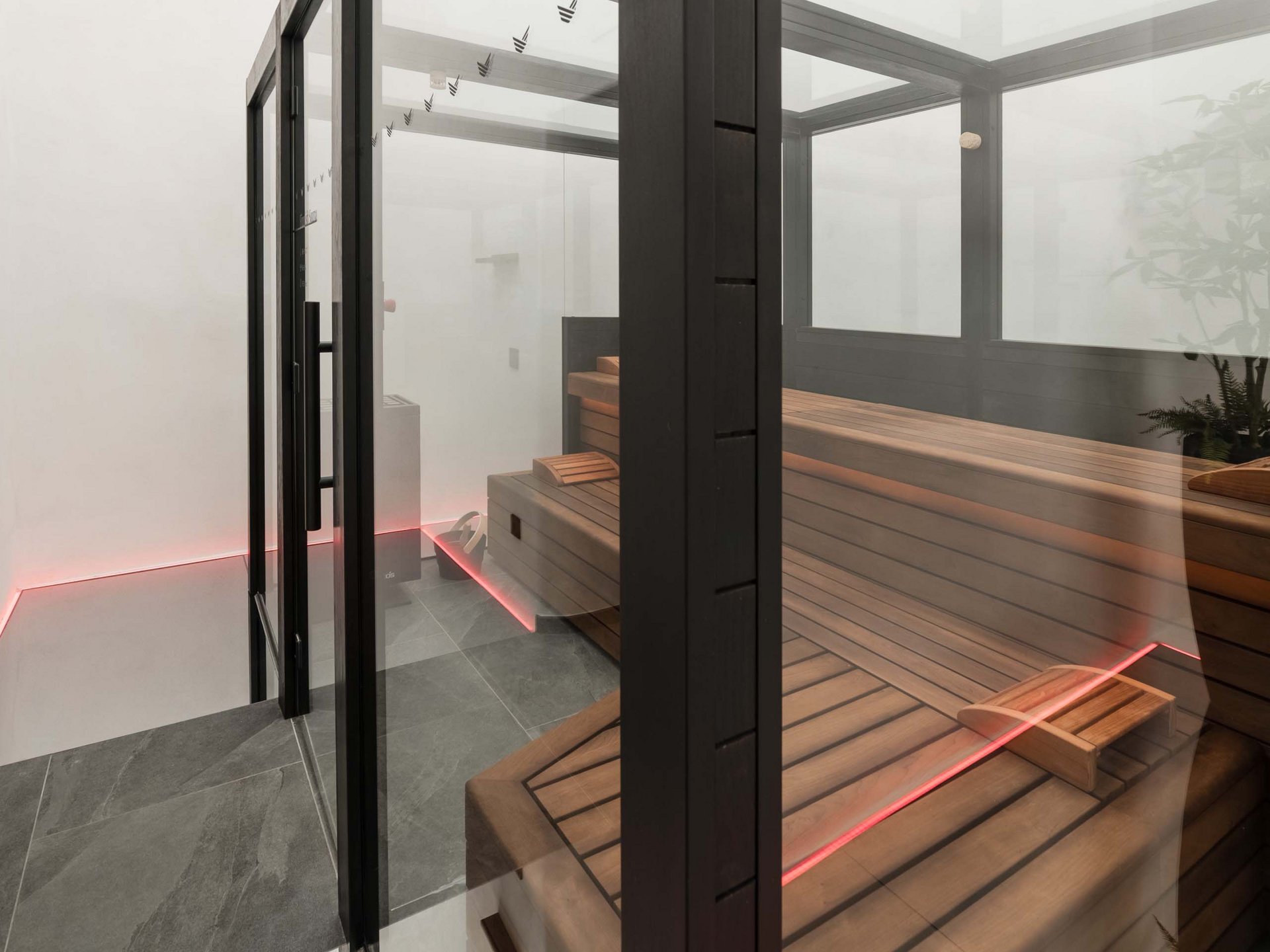 Well-being at the Schwarzer Adler Modern sauna with glass walls and wooden benches in a minimalist room