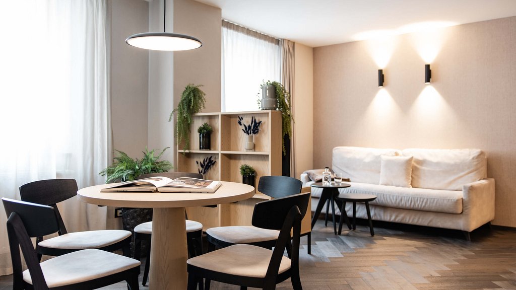 Schwarzer Adler Sterzing: A historic icon. Reinvented. Modernes Wohnzimmer mit Esstisch, vier Stühlen, Sofa und Pflanzen