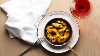 Schwarzer Adler Sterzing: A historic icon. Reinvented. Panierte Teigtaschen mit Sauce und Basilikum auf schwarzer Pfanne und Weinglas