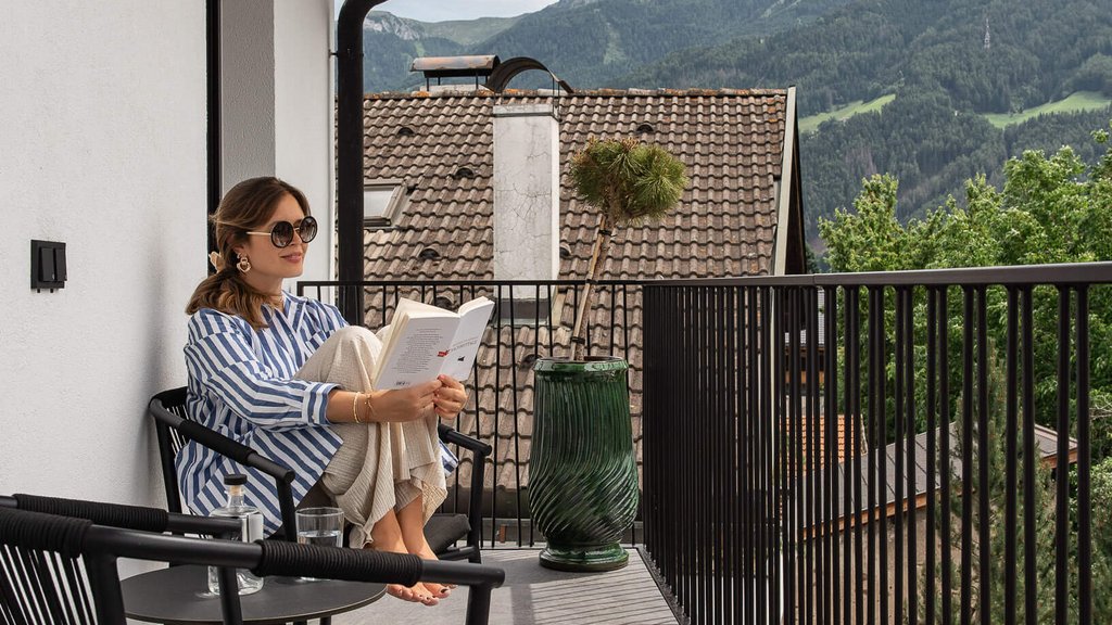 Schwarzer Adler Sterzing: A historic icon. Reinvented. Frau liest entspannt auf Balkon mit Bergblick
