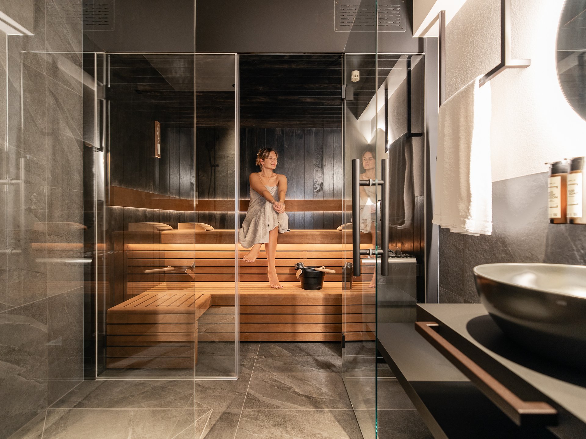 Charmantes Boutique Hotel in Sterzing Frau entspannt in moderner Sauna mit Glaswand und Waschbecken