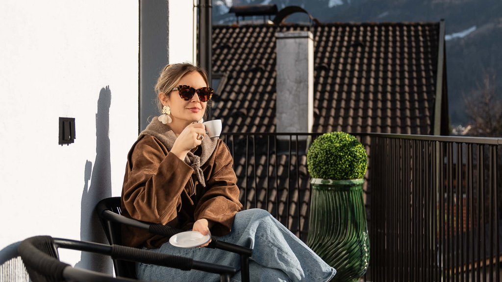 The perfect location for your apartment in Sterzing Woman drinking coffee on balcony with mountain view in sunny weather