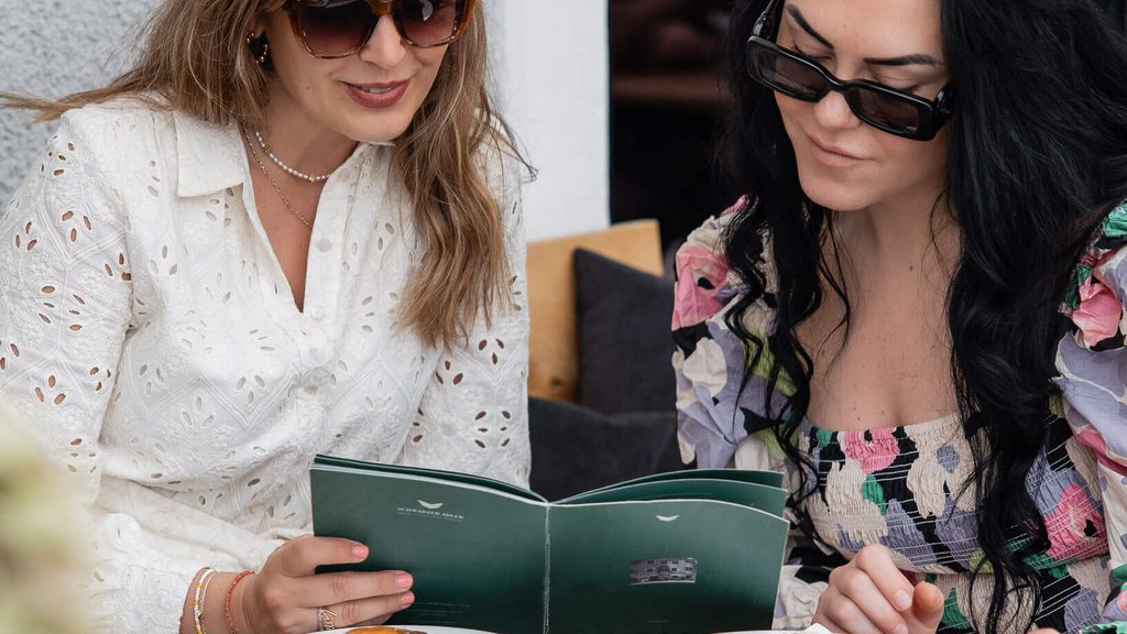 The perfect location for your apartment in Sterzing Two women reading menu with coffee and croissants at a café table