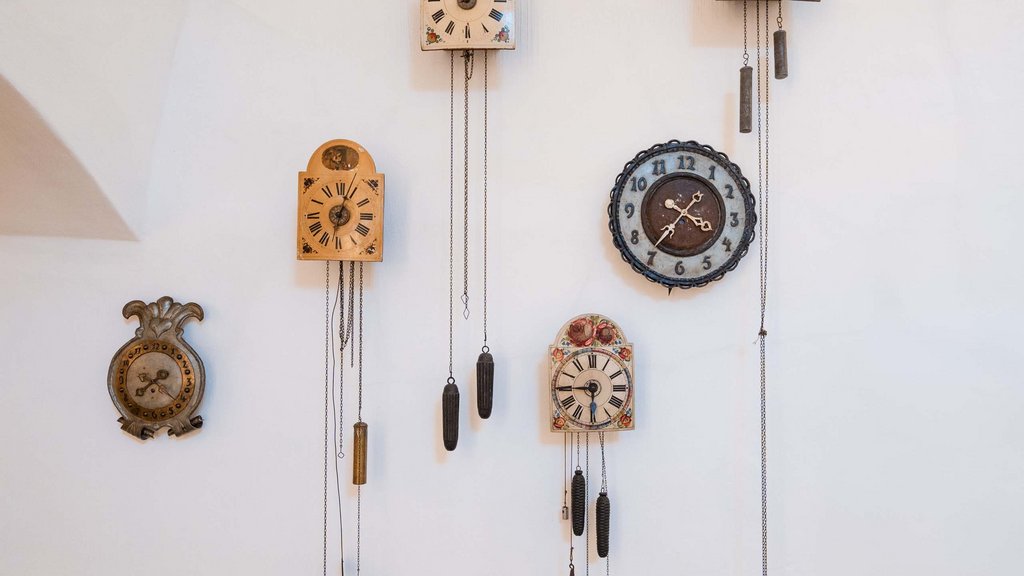 Schwarzer Adler Sterzing: A historic icon. Reinvented. Antike Wanduhren mit Gewichten an einer weißen Wand