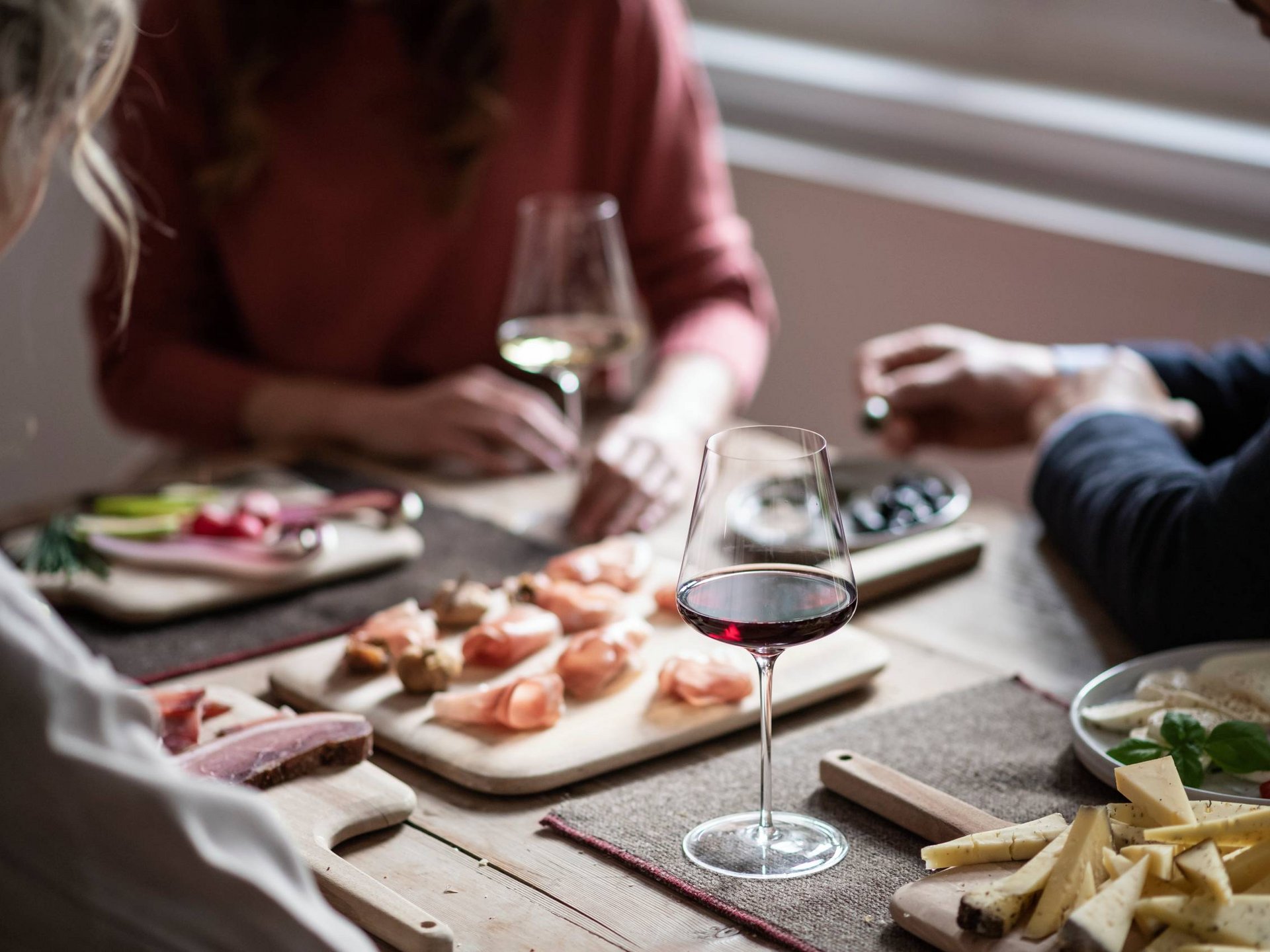 Deliziose boutique, negozi di specialità alimentari Bicchiere di vino rosso e antipasti sul tavolo con persone sullo sfondo