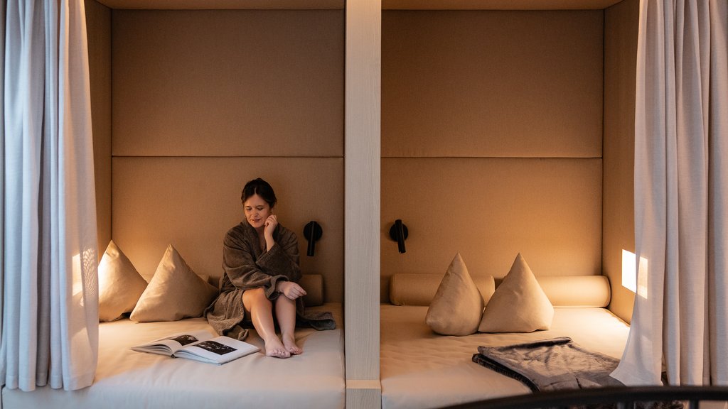 Well-being at the Schwarzer Adler Woman in bathrobe sitting in cozy beige niches with books and pillows