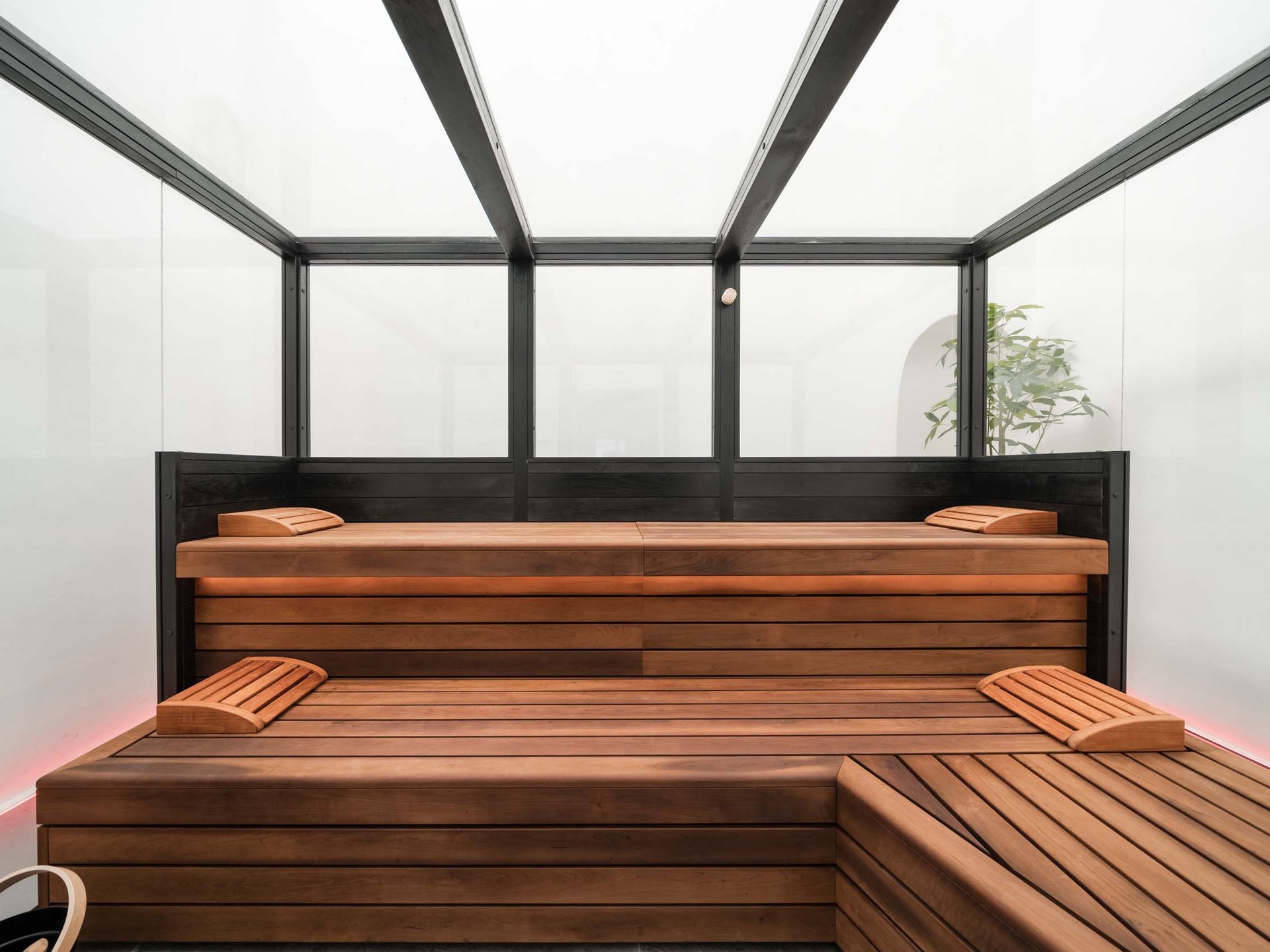 Well-being at the Schwarzer Adler Modern wooden sauna room with benches and headrests, bright walls and glass ceiling