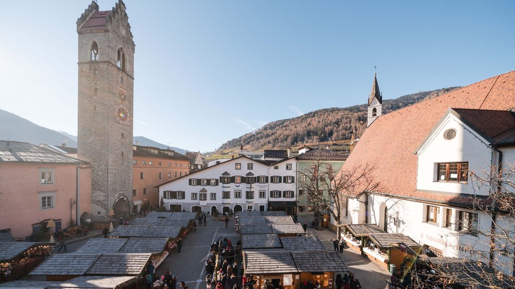 The perfect location for your apartment in Sterzing Market stalls in a historic town square with clock tower and mountains in background