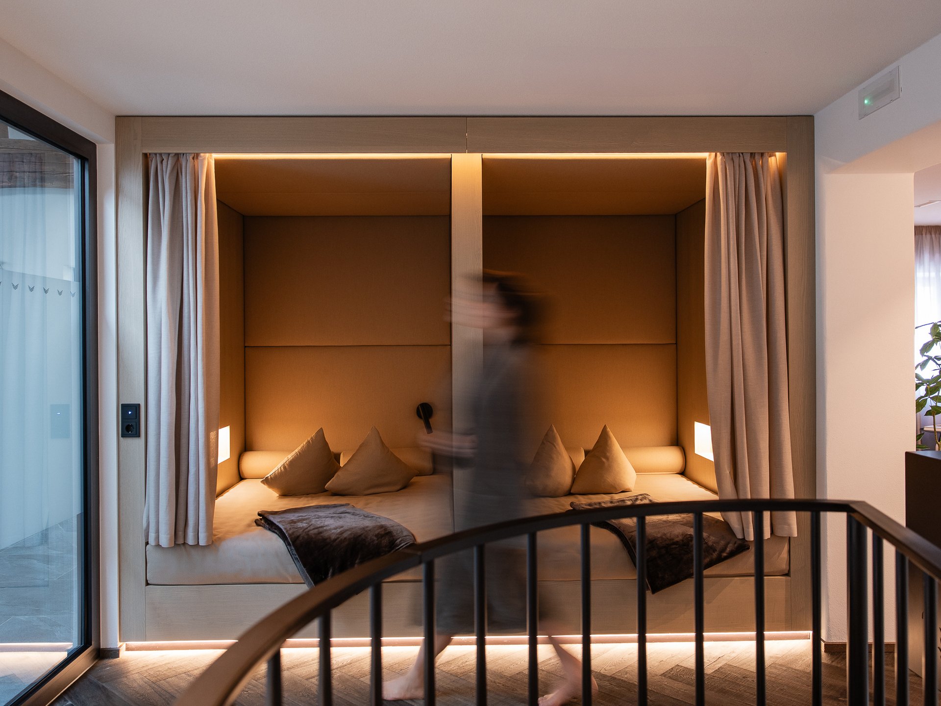 Well-being at the Schwarzer Adler Modern cozy seating nook with brown pillows and curtains in an indoor space