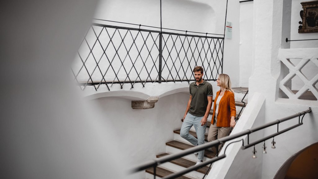The laid-back town on the Isarco/Eisack river Couple walking down stairs in a bright, modern interior