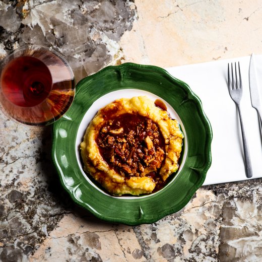 Pamper your palate at this restaurant in Sterzing Polenta with mushroom ragout on green plate and glass of red wine on marble