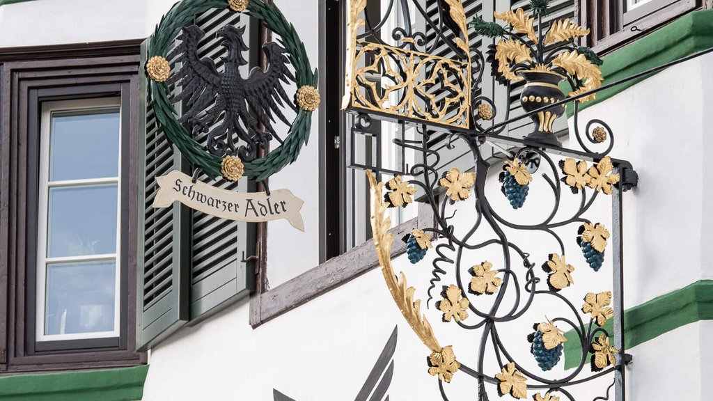 The perfect location for your apartment in Sterzing Schwarzer Adler restaurant sign with gold decorations on white building