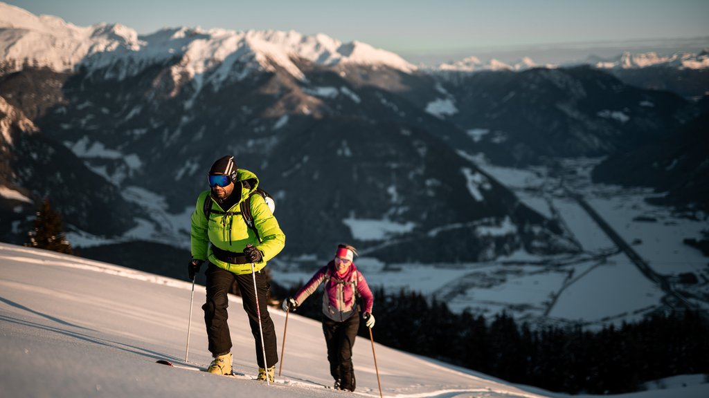 Get your body moving! Two ski tourers climbing snowy slope with Alps mountains in the background