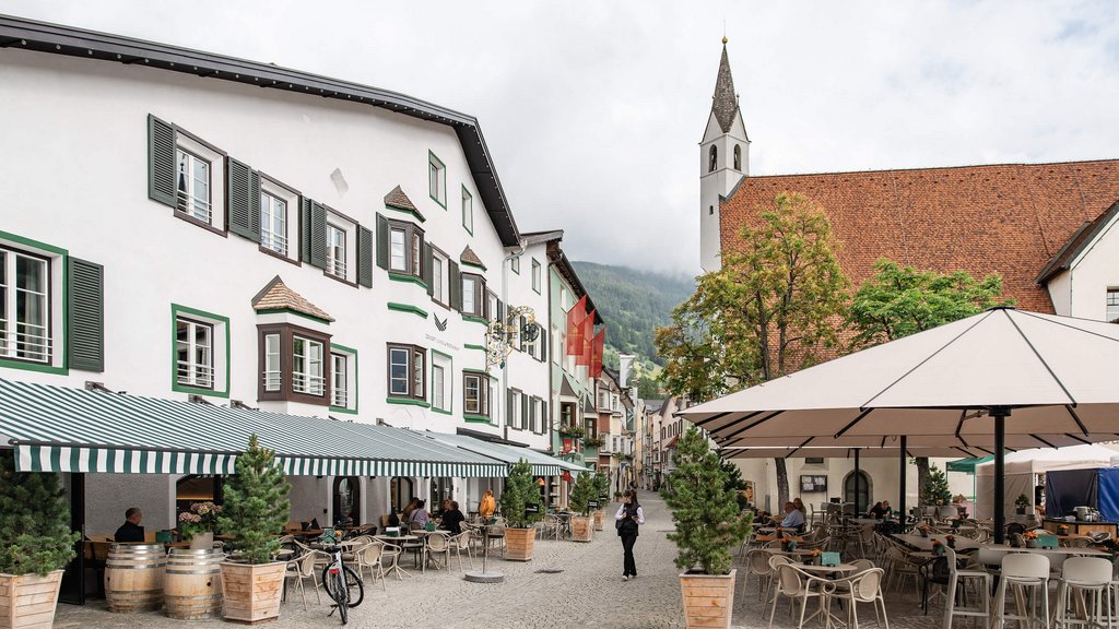 The perfect location for your apartment in Sterzing Outdoor café in a picturesque European village with church and mountains in the background