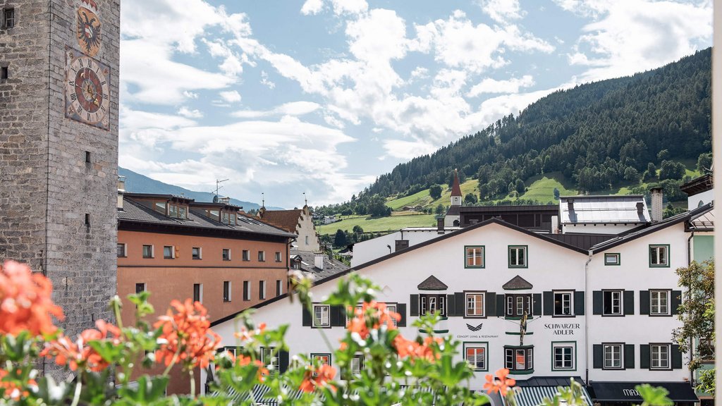 Schwarzer Adler Sterzing: A historic icon. Reinvented. Altstadt mit Turmuhr, Blumen und Bergen im Hintergrund an einem sonnigen Tag