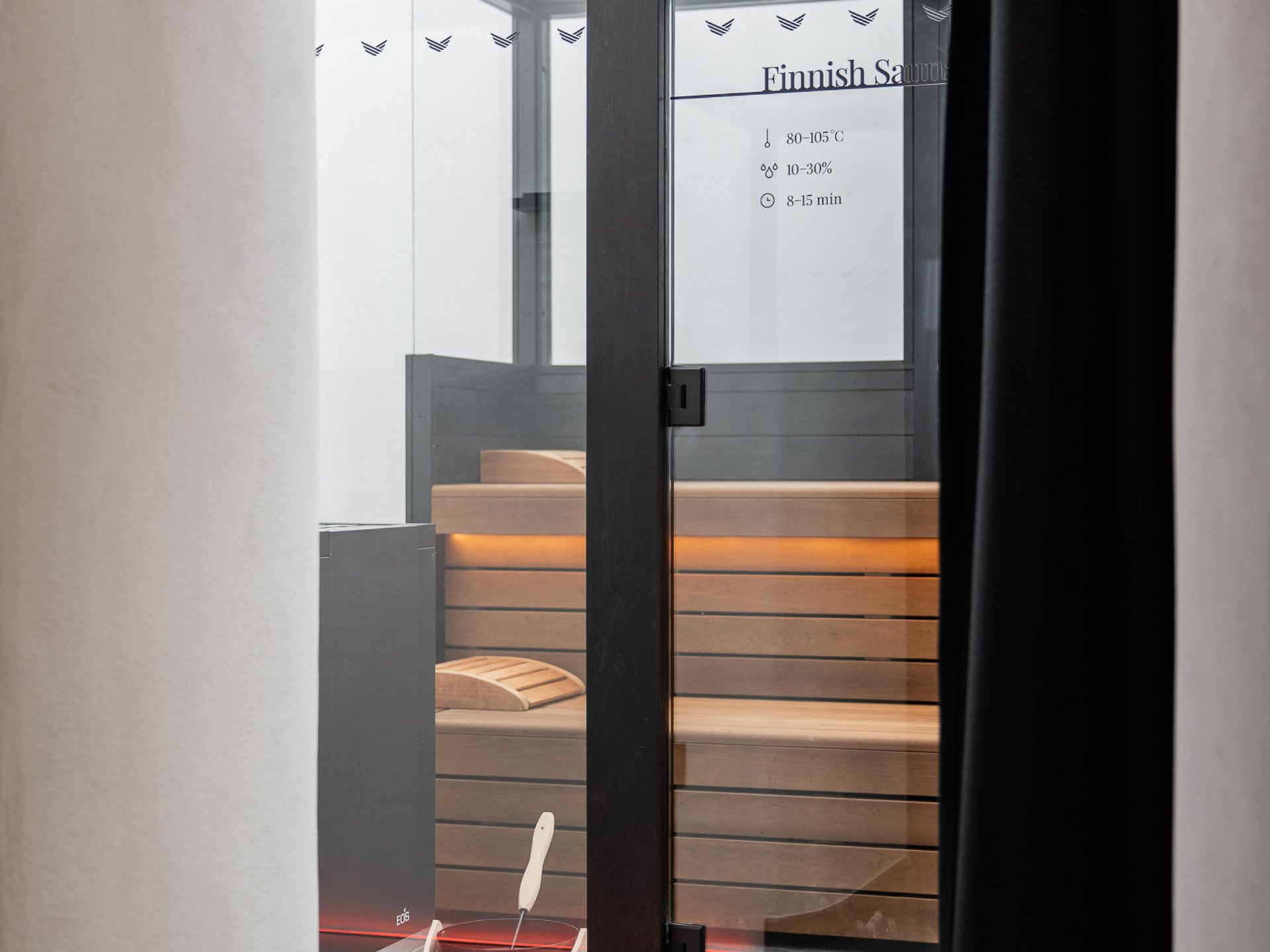 Well-being at the Schwarzer Adler Modern Finnish sauna room with wooden benches and bucket with ladle