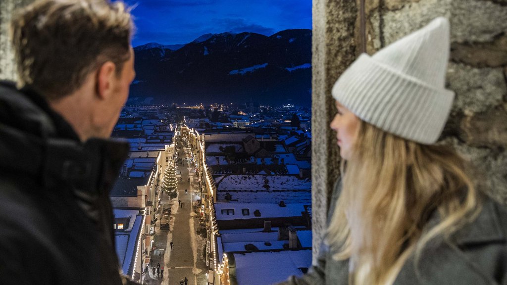 The perfect location for your apartment in Sterzing Couple looking at snowy town with Christmas lights and tree at night
