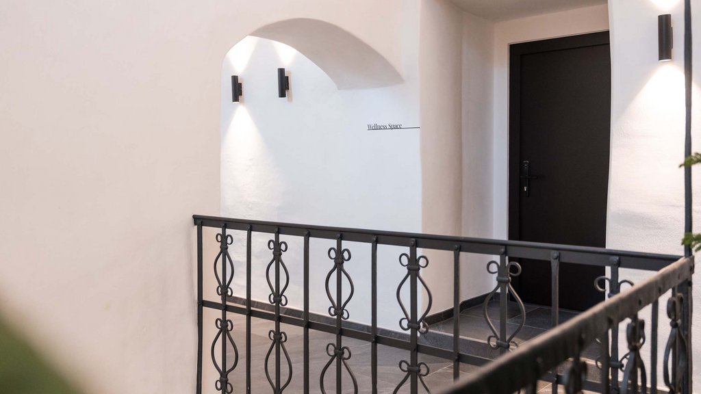 Schwarzer Adler Sterzing: A historic icon. Reinvented. Heller Flur mit schwarzem Geländer und Tür zum Wellnessbereich