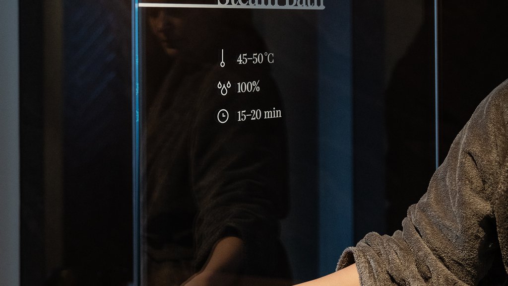 Well-being at the Schwarzer Adler Hand opening glass door of illuminated steam bath in spa