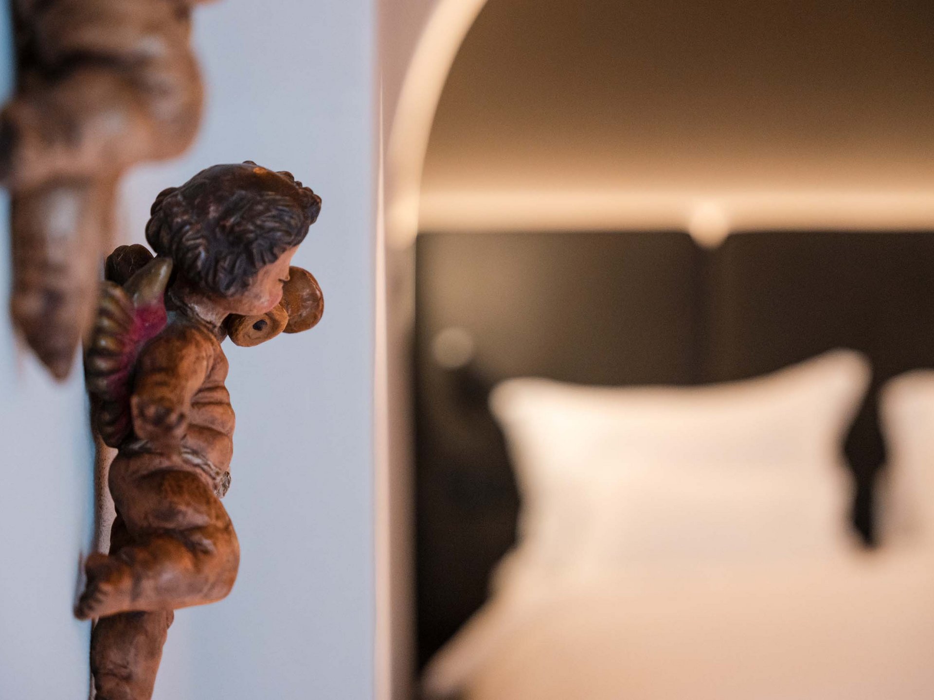 Charmantes Boutique Hotel in Sterzing Holzengel an einer Wand neben einem unscharfen Bett im Hintergrund