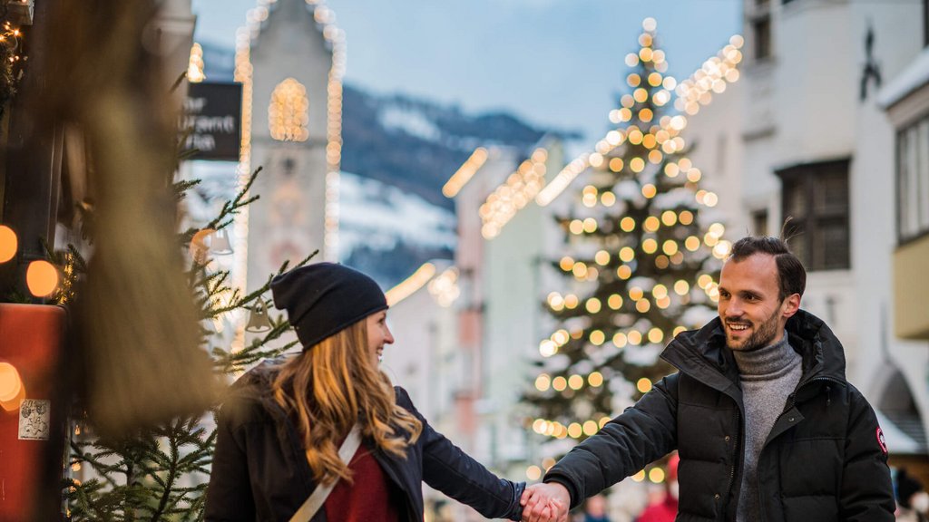The perfect location for your apartment in Sterzing Couple holding hands at a festive Christmas market with lights