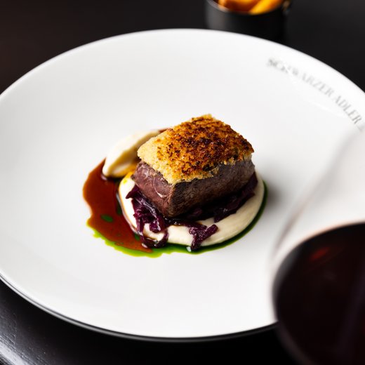 Pamper your palate at this restaurant in Sterzing Gourmet dish with roasted meat, vegetables, and sauce on white plate