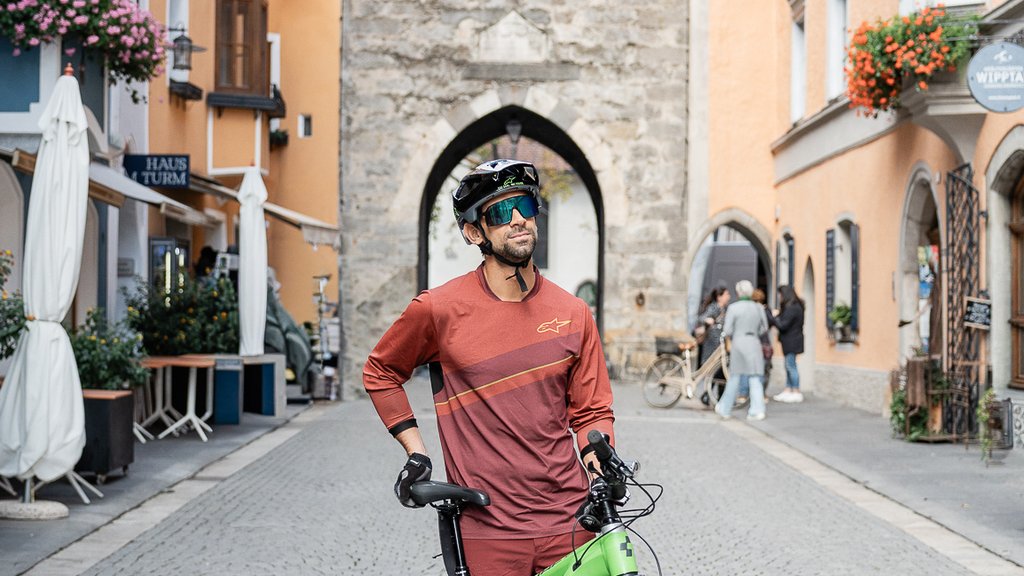 The perfect location for your apartment in Sterzing Cyclist with mountain bike on cobblestone street in front of historic archway