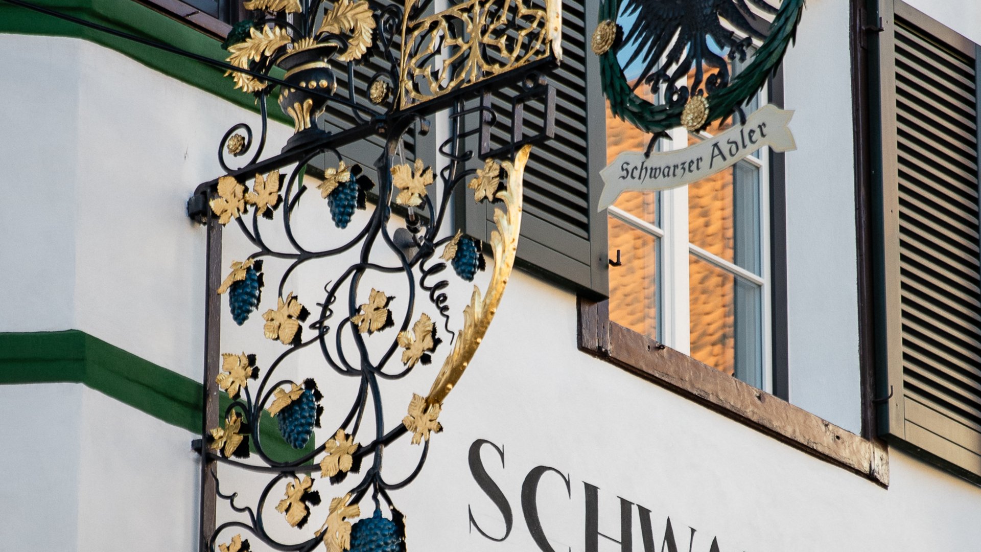 Schwarzer Adler Sterzing: A historic icon. Reinvented. Verzierte schwarze und goldene Metallfassadentafel mit Schrift Schwarzer Adler