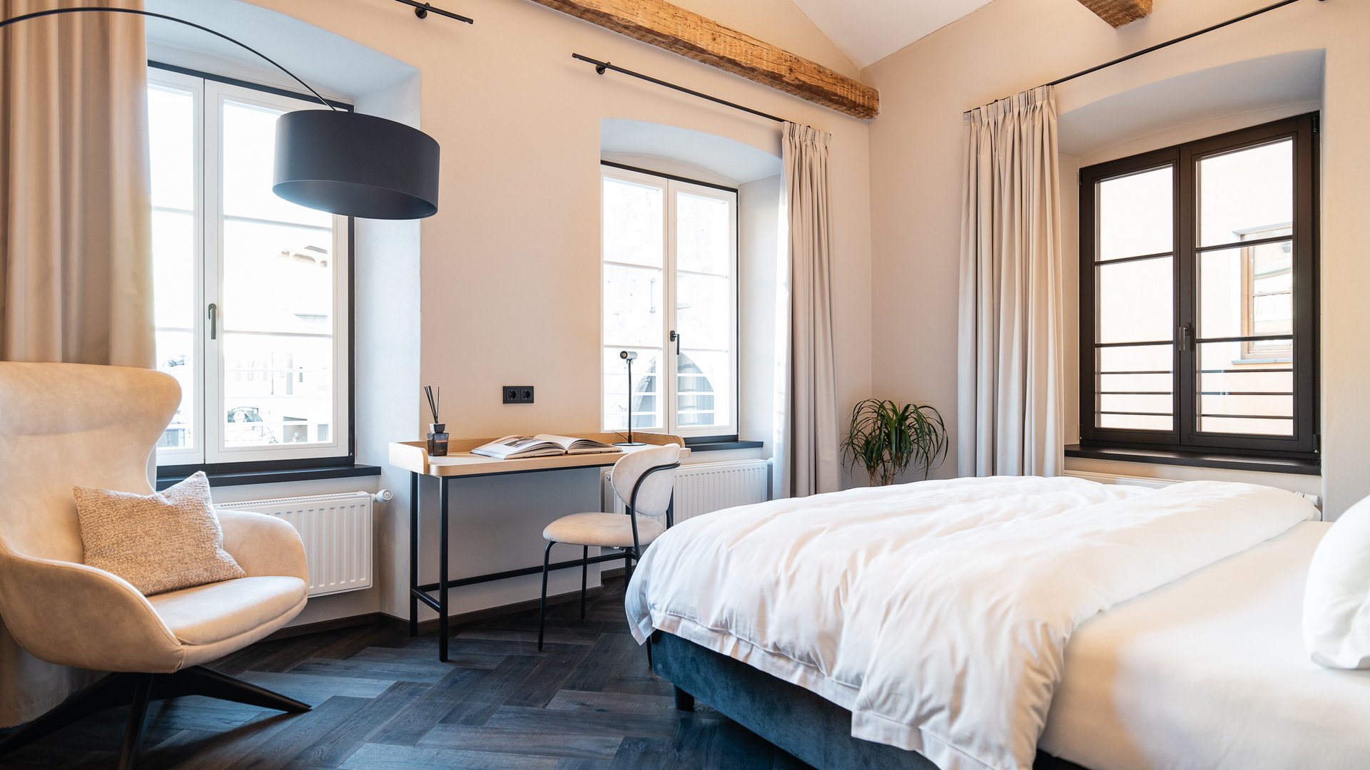 Schwarzer Adler Sterzing: A historic icon. Reinvented. Modernes Hotelzimmer mit großem Bett, Schreibtisch und gemütlichem Sessel