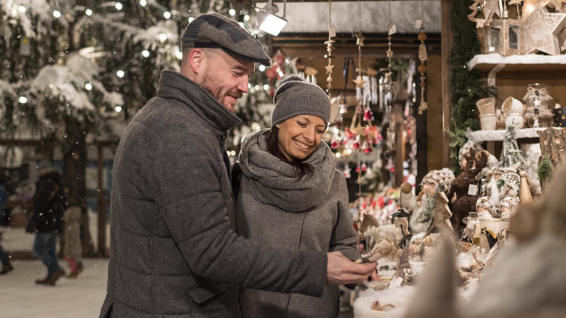 Deliziose boutique, negozi di specialità alimentari Coppia che acquista decorazioni natalizie in un mercatino illuminato
