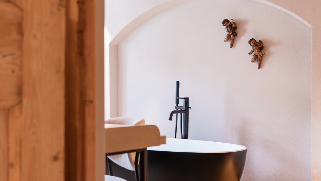 Schwarzer Adler Sterzing: A historic icon. Reinvented. Schwarze Badewanne in hellem Raum mit Holzboden und Deko an der Wand