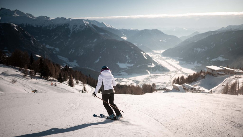 Get your body moving! Skier on slope overlooking snowy Alps and valley