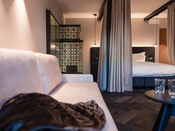 Italian Restaurant Gutscheine Gemütliches Hotelzimmer mit weißem Sofa, Vorhängen und Kachelofen