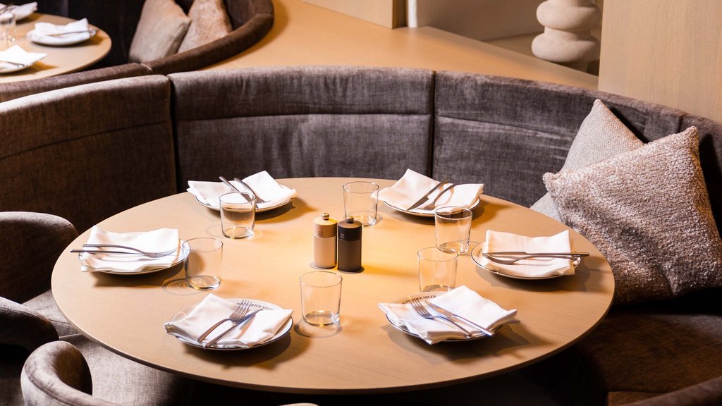 Pamper your palate at this restaurant in Sterzing Round dining table set with cutlery and glasses in a modern restaurant