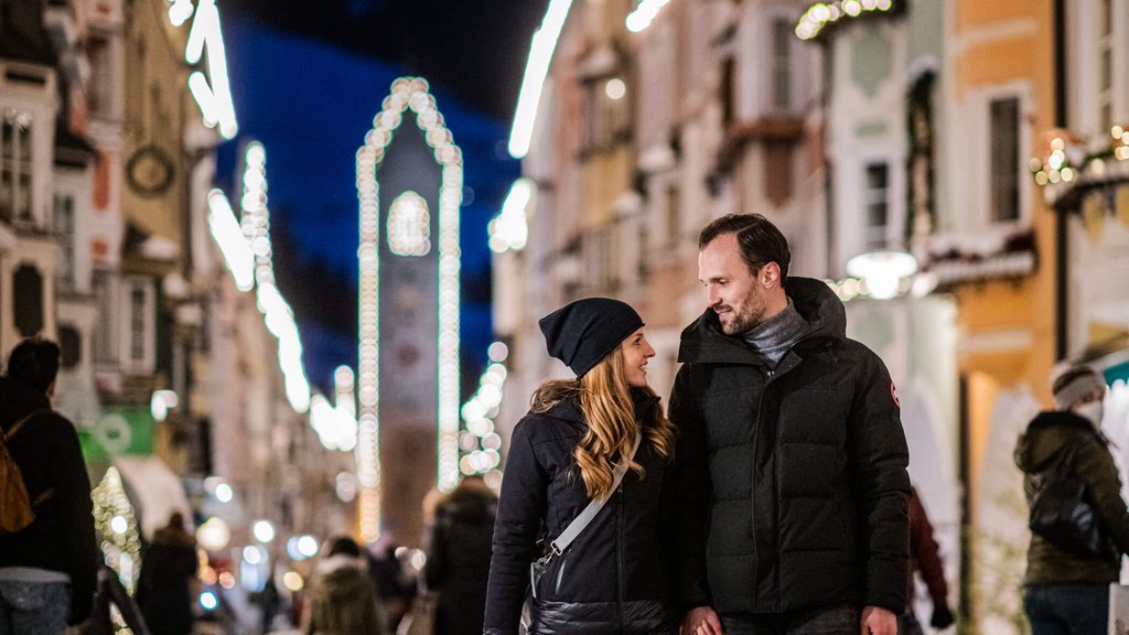 The laid-back town on the Isarco/Eisack river Couple holding hands on a Christmas-lit street in the evening