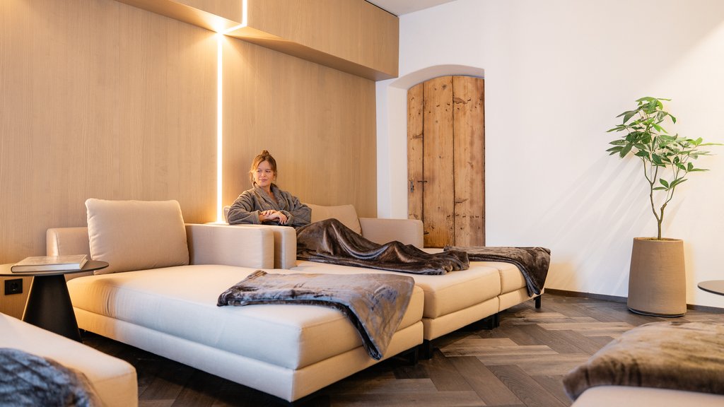 Schwarzer Adler Sterzing: A historic icon. Reinvented. Frau entspannt auf beige Sofa in gemütlichem, modernem Wohnzimmer